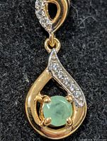 Front view of pendant showing emerald, clear stones and overall design