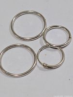 Four silver-tone hoop earrings arranged on flat surface