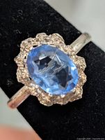 Top view of ring showing blue oval gemstone and halo setting
