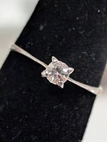 Front view of ring showing round clear stone in four prongs on silver band