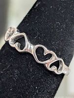 Front view of silver-tone ring showing three open hearts