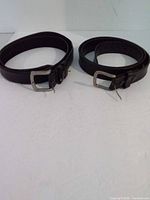 Two black leather belts side by side showing overall condition and buckles