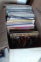 Open box filled with vertically stored vinyl albums, top record visible