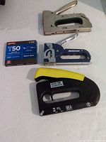 Overall view of three staple guns and box of staples