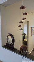 Wide view showing all three items together: elephant, embroidered panel in frame, hanging ceramic wind chime