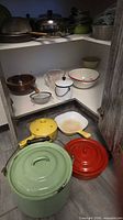overview of assorted cookware and bowls inside cabinet and on floor