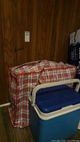 cooler beside red-white check storage bag