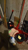 Overall view showing leaf rake, mop bucket, dustpan, cloths, bleach jug and cleanser container