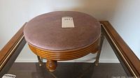 Top view of mauve upholstered round footstool on glass table