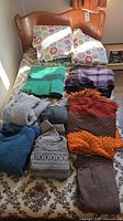 Assortment of six sweaters and four blankets laid out on bed