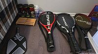 Group shot showing three Head racquets, pickleball paddle, ball cans, pickleball tube and wooden foot massager