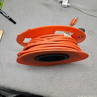 Orange extension cord wound on plastic reel showing plug end