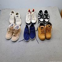 All six pairs of boys shoes laid out on grey surface