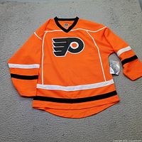 Front view of orange Philadelphia Flyers youth jersey with tags visible