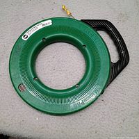 Front view of Greenlee Magnum Pro fish tape reel showing brand labeling, handle, and leader