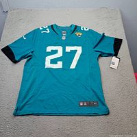 Full front view of teal Jacksonville Jaguars #27 jersey with tags