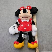 Full view of Minnie Mouse plush with ruler showing height