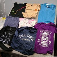 All eight shirts laid out showing colors, graphics, and styles