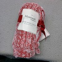 Rolled coral pink velvet throw showing Montauk label and size 50x60, new with tags