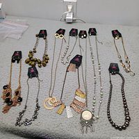 All ten Paparazzi necklace and earring sets laid out on table, each on original card