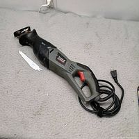 Full view of Task Force reciprocating saw with detached blade and power cord visible