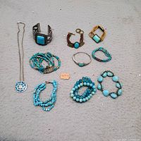 All ten turquoise jewelry pieces laid out on fabric background