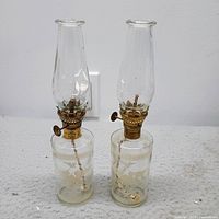 front view of both clear glass oil lamps showing overall design