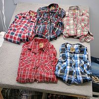 Five plaid Western shirts displayed flat showing fronts