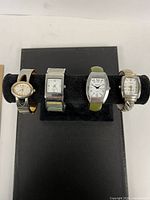 All four wristwatches displayed on stand