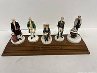 Full view of five figurines on wood base
