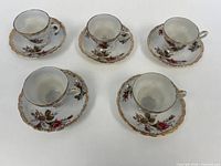 Set of five teacups on saucers arranged top view