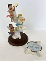 Full view of cherub figurine on base alongside series plaque