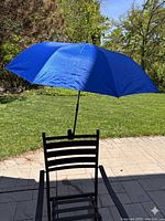 Umbrella clamped to chair fully opened showing blue canopy