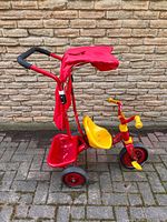 Side view of tricycle showing push handle, canopy and rear bin