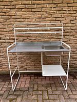 Front view of IKEA SUNNERSTA workstation showing sink, countertop, rail and shelf