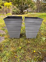 Front view of both planters standing on grass shows overall shape and matching texture.