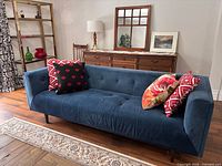 Front view of navy blue velvet tuxedo sofa showing button-tufted seat and arms