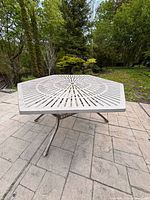 Full view of hexagonal patio table top showing sunburst slat pattern and umbrella hole
