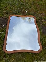 Front view of mirror showing wavy fruitwood frame and clear glass