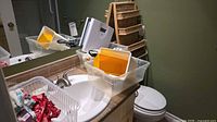 Overall lot showing wicker shelf, plastic bins, scale, dish rack and accessories on bathroom counter