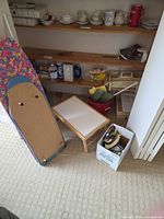 Lot overview showing ironing board, lap tray, iron box, cleaning supplies on shelf