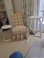 Slipper chair with plaid upholstery and both metal stools displayed