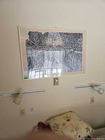 Framed landscape print mounted above wall lights, shows full piece and frame