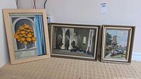 All three framed oil paintings leaning against wall