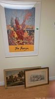 All three framed artworks together: Tom Thomson poster on wall, oil and watercolor on floor
