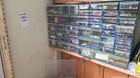 Full view of multi-drawer organizer mounted on wall with contents visible