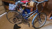 Full left side view of blue Norco bike with pannier and spare saddle on floor