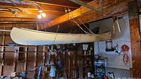 Side profile of white fiberglass canoe suspended from ceiling