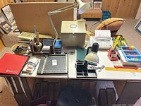 Overall view of office supplies on desk including paper cutter, cash box, lamp, organizers
