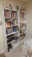 Front view of both white laminate bookcases filled with books